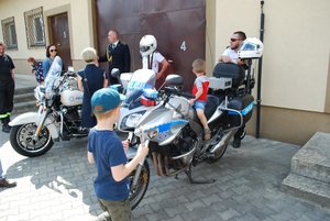 Na zdjęciu policjanci ruchu drogowego w otoczeniu dzieci i rodziców uczestniczących w pikniku oglądających dwa motocykle Harley-Davidson i  Hondę.