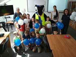 Wspólne zdjęcie dzieci trzymających baloniki , opiekunów, policjantki oraz Pingwina Stefana- maskotki sanockiej Policji.