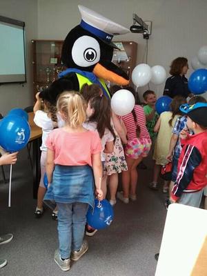 Pingwin Stefan rozdający dzieciom baloniku oraz znaczki z odznakami policjanta.