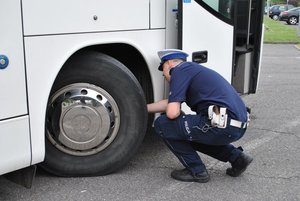 Policjant z wydziału ruchu drogowego podczas kontroli autobusu.