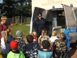 Policjantka prezentuje radiowóz dzieciom.