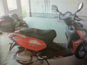 kolorowa fotografia. Czerwony motorower stoi w pomieszczeniu garażowym.