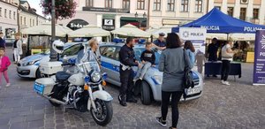 Na Rynku w Rzeszowie podczas pikniku pn &#039;Dzień Serca w Rzeszowie&quot; policjanci prezentują sprzęt służbowy: motocykl Harley-Davidson, radiowozy oraz stoisko profilaktyczne.