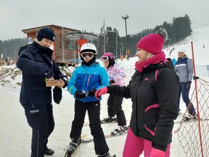 policjantka przekazuje materiały dotyczące działań narciarzom