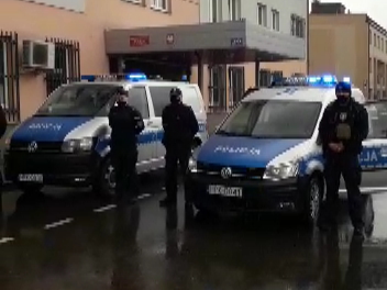 Policjanci stoją między radiowozami ustawionymi przed budynkiem komendy w Dębicy