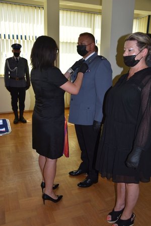 Kobieta przypina policjantowi medal
