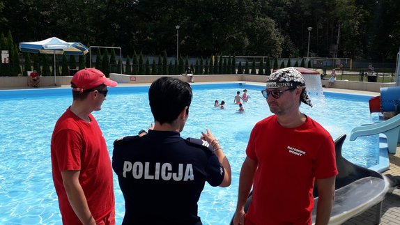 Funkcjonariusze z ratownikami rozmawiają o zasadach korzystania z obiektu pływalni.