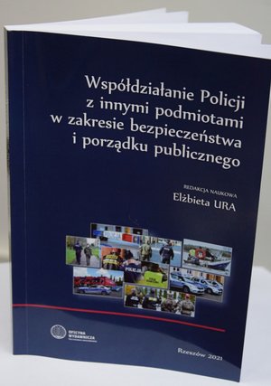 Na zdjęciu książka - Współdziałanie Policji w innymi podmiotami w zakresie bezpieczeństwa i porządku publicznego. Okładka w kolorze granatowym, białe napisy i kolaż kilku zdjęć przedstawiających wspólne działania różnych służb