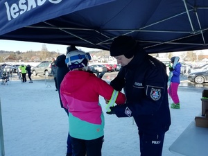 policjant zakłada odblask na rękę narciarza- uczestnika spotkania