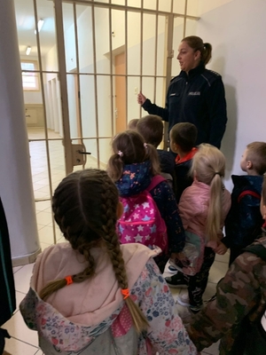 Policjanci pokazują dzieci pomieszczenie dla osób zatrzymanych