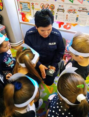 Policjantka pokazuje dzieciom odznakę policyjną