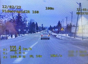 Kadr z nagrania wideorejestratora dokumentujący przekroczenie prędkości przez kierującego samochodem osobowym. W lewym dolnym rogu prędkość pojazdu 121,4 km/h.
