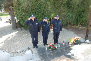 Policjanci oddający honor pod pomnikiem Katyńskim
