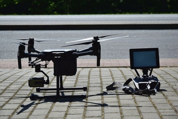 Policyjny dron oraz stojący obok niego panel sterujący z monitorem na chodniku