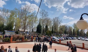 Uczestnicy uroczystości pogrzebowych podczas przejścia na cmentarz komunalny w Krośnie. Na kościelnym placu grupy osób włączające się w kondukt pogrzebowy