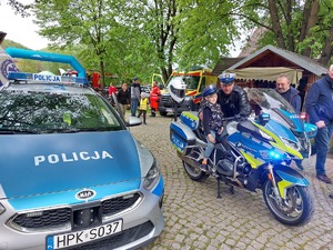 Na zdjęciu osoby uczestniczące w &quot;Dniach Otwartych Funduszy Europejskich&quot; oglądające policyjny motocykl oraz radiowóz.