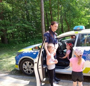 Policjantka z dziećmi przy radiowozie.