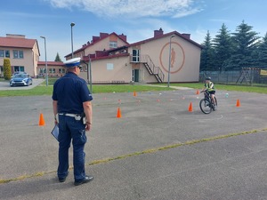Policjant egzaminujący ucznia, który na rowerze pokonuje tor egzaminacyjny