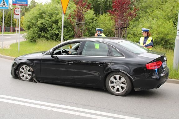 Na zdjęciu pojazd audi oraz dwoje policjantów ruchu drogowego, w umundurowaniu w trakcie czynności na miejscu zdarzenia.