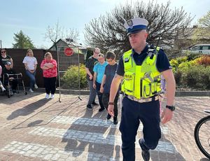 Policjant przypomina młodzieży jak przechodzić przez przejście dla pieszych