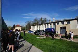 Uczniowie zebrani przed szkoła, gdzie ustawiony był symulator dachowania. W tle widać uruchomiony symulator