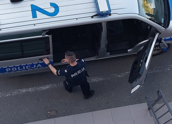 policjant zamyka boczne drzwi radiowozu policyjnego