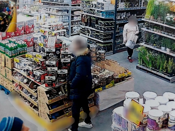 widok z kamery monitoringu na którym widnieją sklepowe półki z ułożonym towarem w tle sylwetka mężczyzny