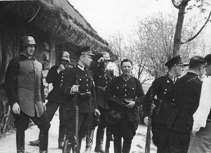 Funkcjonariusze policji przed wejściem do kryjówki bandy Maczugi. Z lewej widoczny policjant w kuloodpornej zbroi płytowej i hełmie, który miał wejść pierwszy do domu bandytów - r. 1934 (zdj. Narodowe Centrum Cyfrowe)