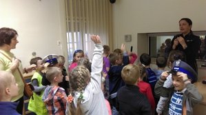 Dzieci wraz z nauczycielem znajdują się w Niebieskim Pokoju i zadają pytania policjantce