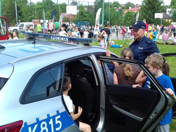 Policjanci pokazują radiowóz dzieciom.