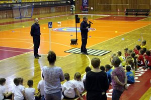 W hali sportowej MOSiR w Tarnobrzegu, dwaj umundurowali funkcjonariusze opowiadają przez mikrofon dzieciom z tarnobrzeskich przedszkoli o zasadach bezpieczeństwa.