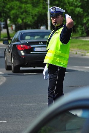 na ulicy umundurowany policjant ruchu drogowego, kieruje ruchem pojazdów.