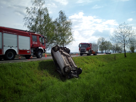 samochód leżący na dachu, w tle wóz straży pożarnej