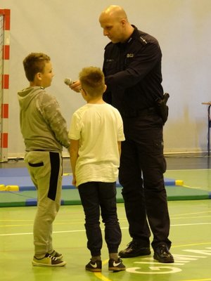 Policjant rozmawia z dwoma uczniami.