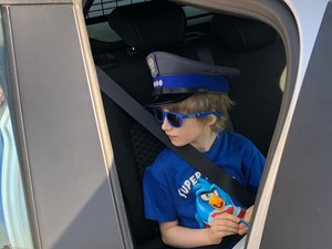 Chłopiec siedzący w policyjnym radiowozie.