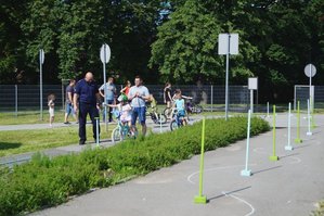 Policjant  obok chłopca pokonującego rowerowy tor przeszkód.