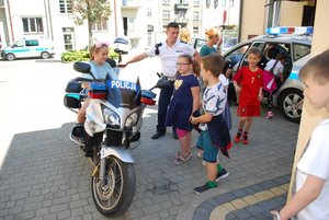 Uczniowie w obecności policjanta oglądają służbowe motocykle.