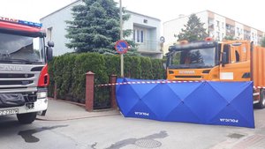 Miejsce zdarzenia - wóz strażacki, policyjny parawan i śmieciarka na skrzyżowaniu ulic