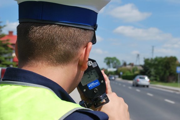 Policjant drogówki podczas pomiaru prędkości laserowym miernikiem.