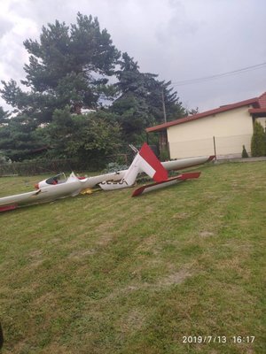 na trawniku znajduje się wrak szybowca, w tle budynek