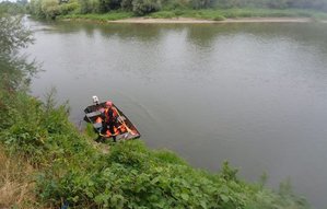 Na fotografii widać rzekę San na której strażacy na łodzi prowadzą akcję poszukiwawczą kobiety.