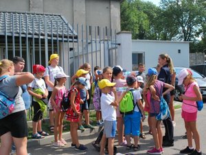 Na fotografii widać dzieci w obecności policjantki która opowiada im o policyjnej służbie.