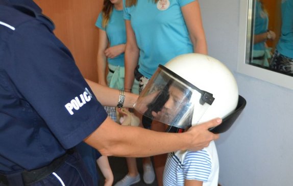 Na zdjęciu widać przedszkolaka, któremu policjantka zakłada hełm