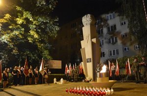 Fotografia przedstawia obchody 80. rocznicy wybuchu II wojny światowej, które odbywają się pod pomnikiem Walk i Męczeństwa w Jarosławiu. Na zdjęciu widoczni są ludzie oraz poczty sztandarowe.