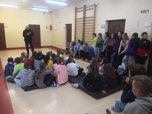 Policjant rozmawia z uczniami Szkoły Podstawowej w Zalesiu.