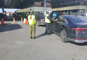 Przejście Graniczne. Policjant wydziału ruchu drogowego kontroluje stan trzeźwości kierującego pojazdem. Za policjantem znajduje się funkcjonariuszka straży granicznej.