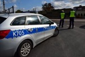 Radiowóz przy którym stoją policjanci i dokonują kontroli drogowej