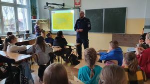 W klasie szkolnej policjant prowadzi prelekcje dla uczniów Szkoły Podstawowej w Jasionce.