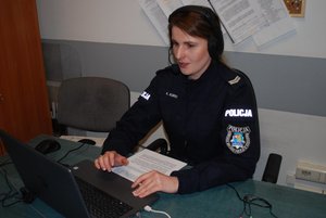 Na zdjęciu policjantka siedząca za komputerem i prowadząca spotkanie on-line.