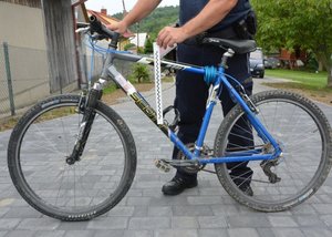 Policjant który dokonuje oględzin roweru biorącego udział w zdarzeniu drogowym